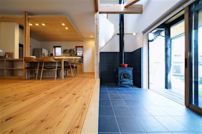 土間サロンの主役は薪ストーブ。屋外からの薪の補充がスムーズにでき、掃除もしやすい機能的なつくり。階段と絡めた幅広の吹き抜けを通して、暖かさが二階までいきわたる。