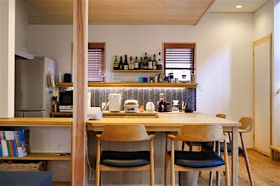 L字のキッチンカウンターはダイニングテーブルを兼ねる。大きな作業台にもなり、配膳もしやすく、省スペースで効率の良い設計。子ども達が寝たあとに、ご夫婦水入らずでグラスを傾けるのにもぴったりの、バーのような洒落たデザイン。