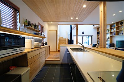 キッチンの床は土間サロンと同じタイル張り。床レベルをあえて一段下げることで、正面のカウンターに腰かけるご家族と目線が揃う。家族が集うキッチンダイニングにぴったり。