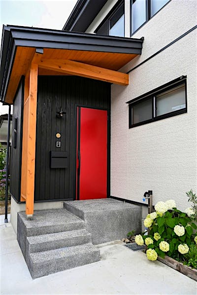 モノトーンをベースにまとめた外観に、鮮やかな赤色の玄関ドアが個性的なファサード。