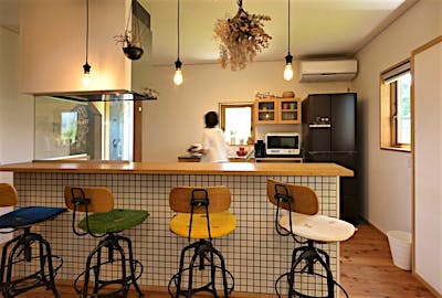家族並んで食事ができる、対面カウンターのキッチン。腰高のタイル張りと裸電球のソケットランプが、空間のアクセント。