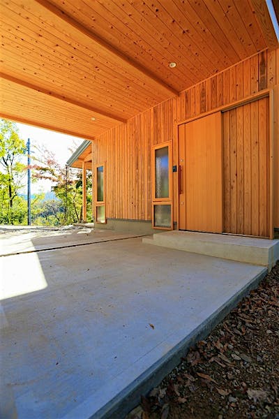 玄関に直結するカーポート。玄関ドアも造作の木製引き戸。