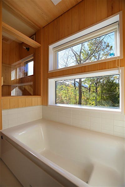 ハーフユニットバスからの立ち上がりはタイル仕上げ。木部はヒノキ材。バスタブからも山の景色を存分に楽しめる。