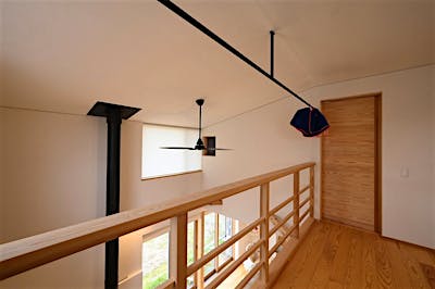 吹抜け手摺は木製の横格子。目線が通るので広々する。天井にはアイアンの物干しを計画。