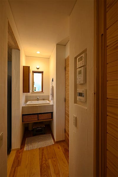 リモコン類はニッチ棚におさめた。洗面台も自然光が入り明るい。タイル仕上げなので水はねも安心。