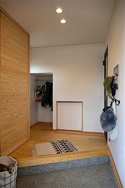 玄関ホールには階段下を活用したコート掛け。左手には大容量の玄関収納。