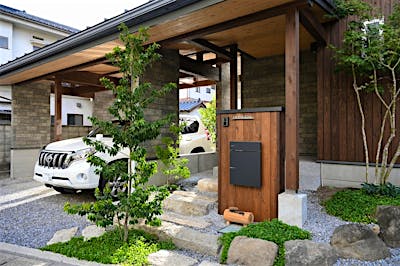建物一体型のカーポートや石積みのアプローチ、植栽、門柱。家の顔になるからとことんこだわった。
