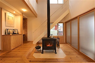 薪ストーブはIRONDOG No4。炉台モカクリームタイル。クリアの3枚扉の向こうには玄関が。