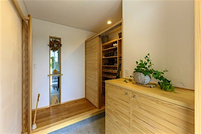 玄関には季節を感じるしつらえが出来るスペースを。正面のガラス窓の向こうに見えるのは土間サロン。