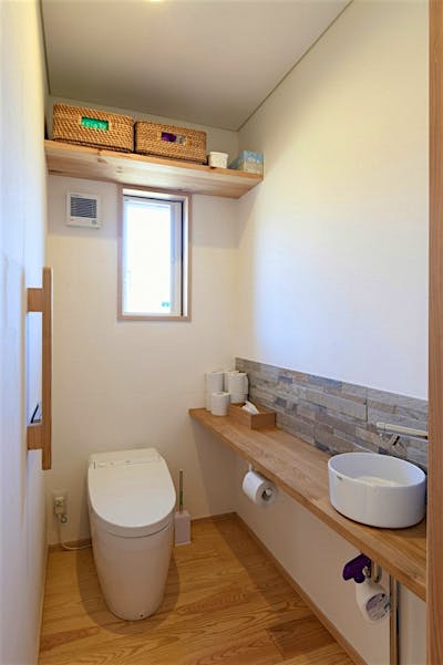 石調タイルがアクセントの明るいトイレ。