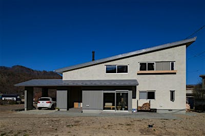 高さを抑えた片流れ屋根のファサード。ガレージ、玄関、土間まで大きく伸びた下屋が美しい水平ラインを強調する。