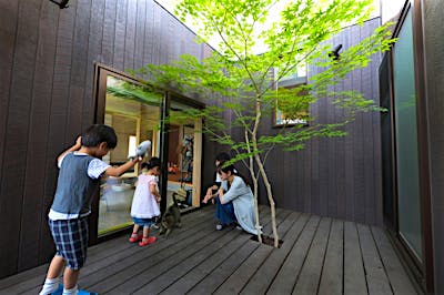 土間の隣のウッドデッキは、コの字の建物と縦格子に囲まれたプライベートな空間。中央に配したシンボルツリーが空間を印象的に演出。