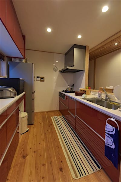 キッチンはアクセントカラーの赤。無垢の素材感の中で目を引くキッチンに。