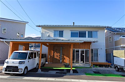 カーポート、玄関、土間サロンを一枚の屋根でおさめた。外部の色味を軽やかにすることで重くなりすぎない印象に。