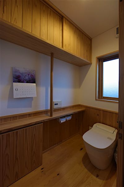 幅を広めに設計したトイレは、収納棚と手すりを木製で造作。日用品をきちんと収納できてすっきりと使える。