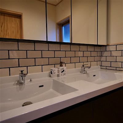 洗面台の壁とキッチンには揃いのタイルをコーディネイトした。二つの洗面台は娘さんと二人並んで化粧をする、という奥様の夢から。