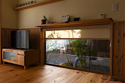 お母様のリビングからは、地窓を介して中庭を望む。若夫婦世帯と真向いの位置ながら、地窓と高窓で視線をずらして気兼ねなく景色を眺められる、プランニングの妙。