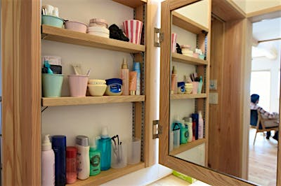 洗面の収納は開くと鏡が現れる。可動棚でしまうものの高さに合わせられるので、しっかりスッキリ収納できる。