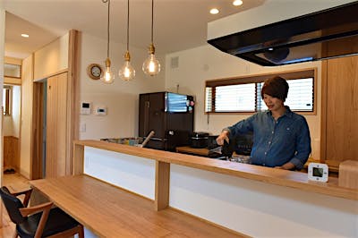 手元が隠れるカウンターキッチンですっきりと。三灯連なる真鍮製ペンダントライトにセンスが光る。