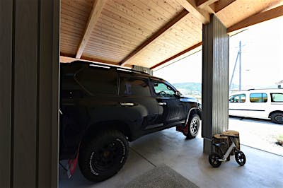 玄関ポーチを兼ねたカーポートが、家のファサードに表情をつける。板張り天井は一部天窓で明るさも確保。