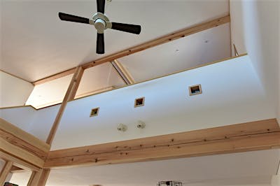 開放的な吹き抜け。腰壁に埋め込んだ四角い3つのステンドグラスは、信州の山と四季をテーマに、ご家族3人で手作りした。