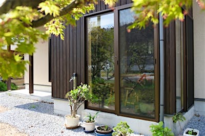 外部の板張りやサッシ色も落ち着いた色味を選択。既存の庭や土蔵としっかり調和する。