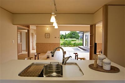 キッチンからの眺め。リビングダイニングと、フルオープンサッシの向こうに庭と安曇野の景観を一望できる。