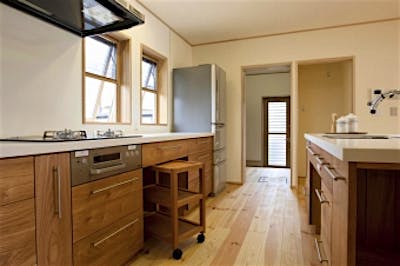 木製の造作キッチンは、Ⅱ型のセパレートキッチン。娘さんと一緒に料理をするときにも使い勝手が良い。奥にはワインセラーを置ける広々パントリーと勝手口。